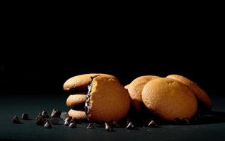 Biscuits filled with chocolate cream. Chocolate cream cookies. brown chocolate biscuits with cream filling on black background. photo