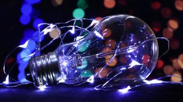 One light bulb lies on a black background with lights in the background. Creative ideas concept. Colorful background with flickering light bulbs. Holiday concept. New Year's and Christmas photo