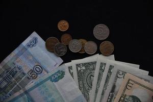 billetes de dólar y rublos con monedas en un fondo negro foto