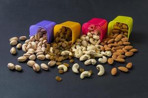 Healthy Mix Dry Fruits and Nuts on dark background. Almonds, Pistachio, Cashews, Raisins photo