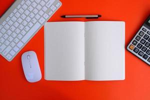 Notebook with pen are on top of office desk table with computer tools and supplies. Top view with copy space, flat lay.  Finance and banking advertising photo