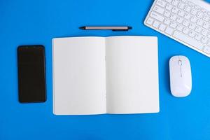 Notebook with pen are on top of office desk table with computer tools and supplies. Top view with copy space, flat lay.  Finance and banking advertising photo