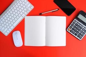 Notebook with pen are on top of office desk table with computer tools and supplies. Top view with copy space, flat lay.  Finance and banking advertising photo