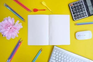 Blank notebook with pen are on top of blue office desk table with computer tools and supplies. Top view with copy space, flat lay. photo