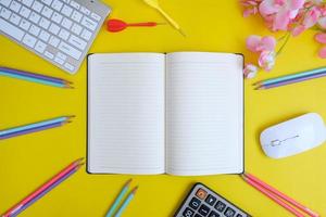 el cuaderno en blanco con bolígrafo está encima de la mesa de escritorio de oficina azul con herramientas y suministros informáticos. vista superior con espacio de copia, plano. foto