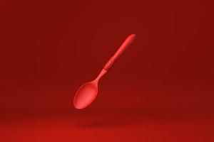 cuchara roja flotando en un fondo rojo. idea de concepto mínimo creativo. monocromo. procesamiento 3d foto