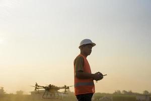 ingeniero masculino que controla la fumigación de fertilizantes y pesticidas con drones sobre tierras de cultivo, innovaciones de alta tecnología y agricultura inteligente foto