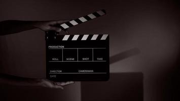 Hand holds empty film making clapperboard on color background in studio photo