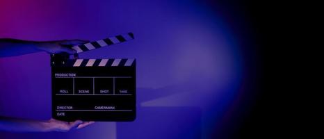 Hand holds empty film making clapperboard on color background in studio photo