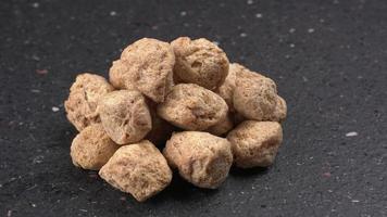 Raw soya chunks on dark background. Healthy, nutritious soybean meat, chunks isolated.Vegan food concept. photo