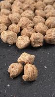 Raw soya chunks on dark background. Healthy, nutritious soybean meat, chunks isolated.Vegan food concept. photo