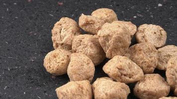 Raw soya chunks on dark background. Healthy, nutritious soybean meat, chunks isolated.Vegan food concept. photo