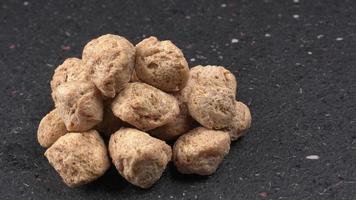 Raw soya chunks on dark background. Healthy, nutritious soybean meat, chunks isolated.Vegan food concept. photo