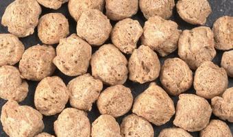 Raw soya chunks on dark background. Healthy, nutritious soybean meat, chunks isolated.Vegan food concept. photo