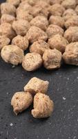 Raw soya chunks on dark background. Healthy, nutritious soybean meat, chunks isolated.Vegan food concept. photo