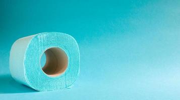 Blue roll of modern toilet paper on a blue background. A paper product on a cardboard sleeve, used for sanitary purposes from cellulose with cutouts for easy tearing. Embossed drawing. copy space. photo