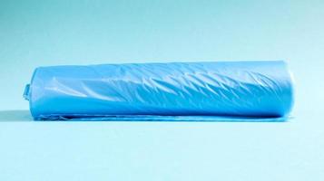 One roll of plastic garbage bags in blue on a blue background. Bags that are designed to accommodate garbage in them and used at home and placed in various garbage containers. photo
