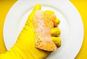 esponja de limpieza en un plato blanco sobre un fondo amarillo foto