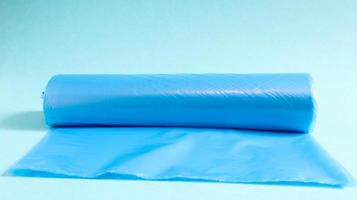 One roll of plastic garbage bags in blue on a blue background. Bags that are designed to accommodate garbage in them and used at home and placed in various garbage containers. photo