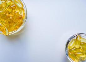 Fish oil capsules on a glass plate. A lot of vitamin omega 3 on a white background. Close-up, top view, high resolution product. Metabolism in the body. The body of calcium. A quick way to lose weight photo