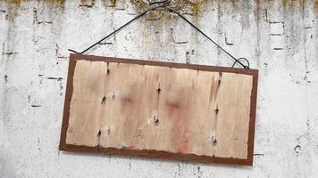 colgando un cartel de madera en una pared de hormigón gris. marco en una pared de cemento. un gran cartel de madera colgado de una cuerda con una pared de hormigón. copie el espacio foto