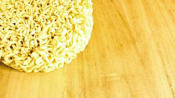 Raw instant noodles on a wooden plate with copy space to add text on the background. pasta, for the preparation of which it is enough to pour boiling water and wait a few minutes. photo