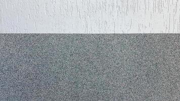 Gray marble chips and decorative light stucco on the wall divided by a horizontal line. Building facade background. Stucco texture on the street photo