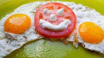fried eggs with vegetables on a green plate, served to children photo