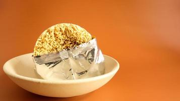 Raw instant noodles in a deep bowl for soup in an open condition from an unnamed foil packaging without a name close-up. pasta, for the preparation of which it is enough to pour boiled water. photo