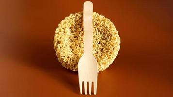 fideos instantáneos crudos en forma de círculo con un tenedor desechable de madera. pasta, para cuya preparación es suficiente verter agua hirviendo y esperar unos minutos. espaguetis. copie el espacio foto