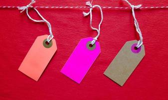 Three colored bright tags hang on a red rope on a red background. Copy space, place for text, flat lay. photo