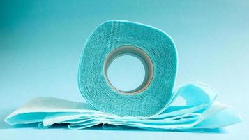 Blue roll of modern toilet paper on a blue background. A paper product on a cardboard sleeve, used for sanitary purposes from cellulose with cutouts for easy tearing. Embossed drawing photo