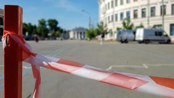 Red white does not cross the tape and the metal pole. Signal red and white tape hanging on a metal fence, danger, warning. Ribbon and metal red post. Forbidden tape encloses an unsafe area. photo