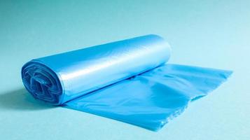 One roll of plastic garbage bags in blue on a blue background. Bags that are designed to accommodate garbage in them and used at home and placed in various garbage containers. photo