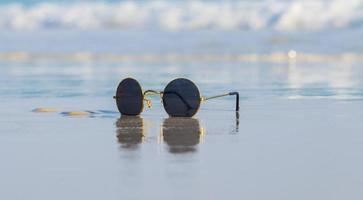 gafas de sol en la arena hermosa playa de verano foto