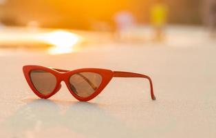 sunglasses on sand beautiful summer beach and golden light of sunset photo