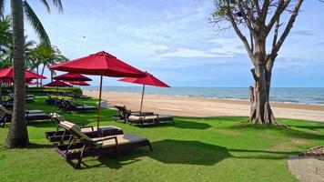 roter Regenschirm und Strandkorb mit Meeresstrandhintergrund und blauem Himmel und Sonnenlicht video