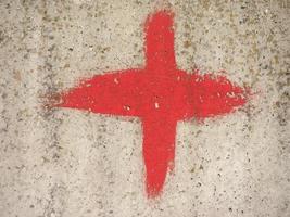 cruz roja sobre fondo de textura de hormigón gris foto