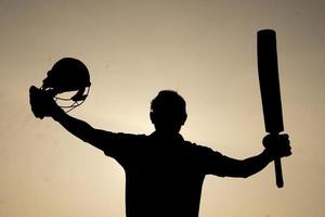 silueta de un jugador de cricket celebrando después de ganar un siglo en el partido de cricket. jugadores de críquet indios y concepto deportivo. foto