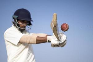 un jugador de críquet jugando al cricket en el campo vestido de blanco para los partidos de prueba. deportista golpeando un tiro en la pelota de cricket. foto