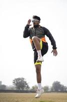 Young Indian boy exercising and jumping on the sports field. Sports and healthy lifestyle concept. photo