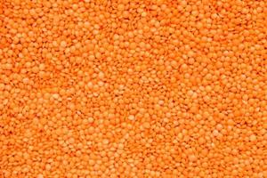 Scattered raw red lentils as background texture photo