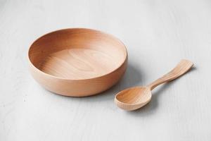 Empty wooden bowl and wooden spoon on a white table background photo