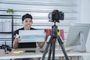 asian man blogger present and review product video broadcast live stream video to a social network. blogging, vlogging, online shopping, and social media concept photo