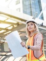 Foreman engineer female businesswoman manager wear safety work job report draw sketch look site project industry construction technology digital import export warehouse building construction city photo