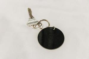 Hotel room key with round black blank pendant white background. photo