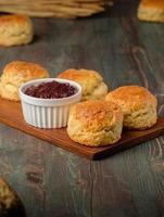 group of scones on wood plate with jam on table photo