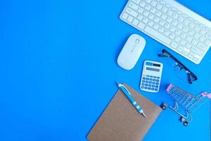 la mesa de oficina con herramientas y suministros informáticos es un cuaderno en blanco con un bolígrafo. endecha plana, vista superior con espacio de copia. foto