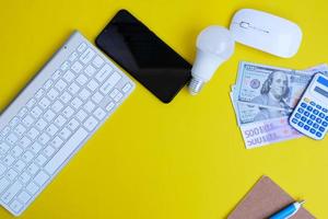 Top view on working space with office equipment and space for text,  concept of money on a yellow background represents finance and banking photo