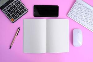 Notebook with pen are on top of office desk table with computer tools and supplies. Top view with copy space, flat lay.  Finance and banking advertising photo